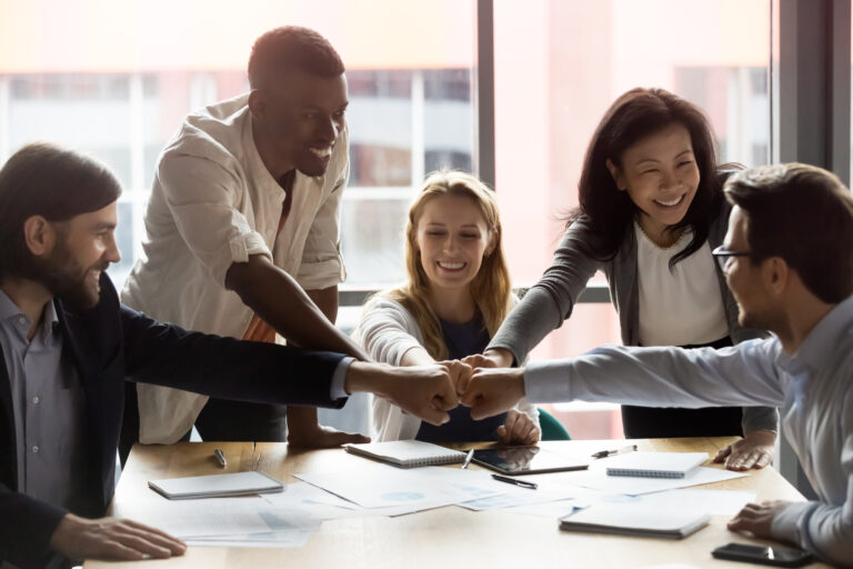 Happy diverse employees team joining fists, celebrating success