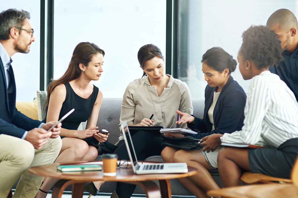 Image of business professionals sitting around a table conversing.