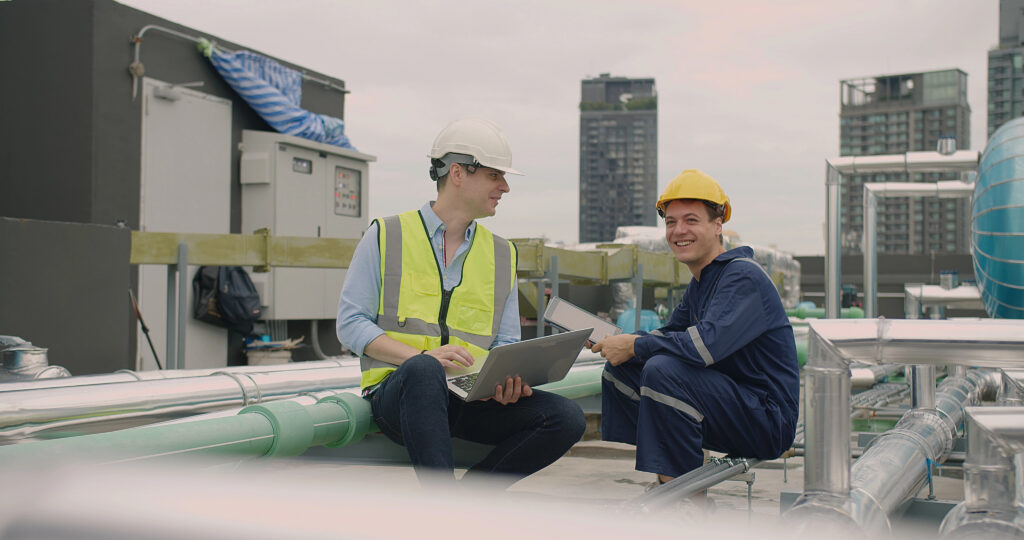 Image of two maintenance workers sitting and conversing on the roof of a building.