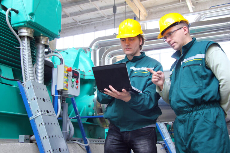 Manufacturing professionals reviewing operational data in a production facility, supporting workforce planning, talent acquisition, and manufacturing RPO initiatives.