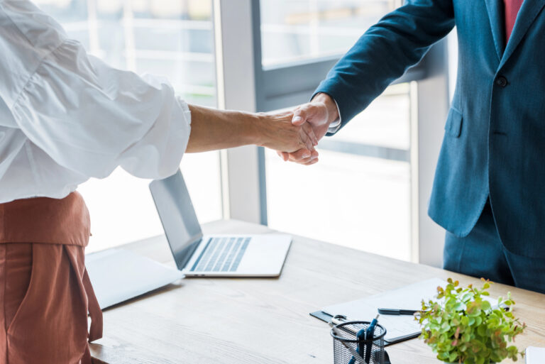 Business professionals shaking hands during a meeting, representing leadership hiring, executive decision-making, and strategic business partnerships.