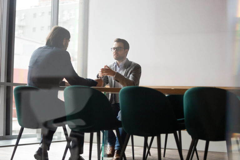 Business professionals conducting an administrative staffing interview in a corporate office meeting room.