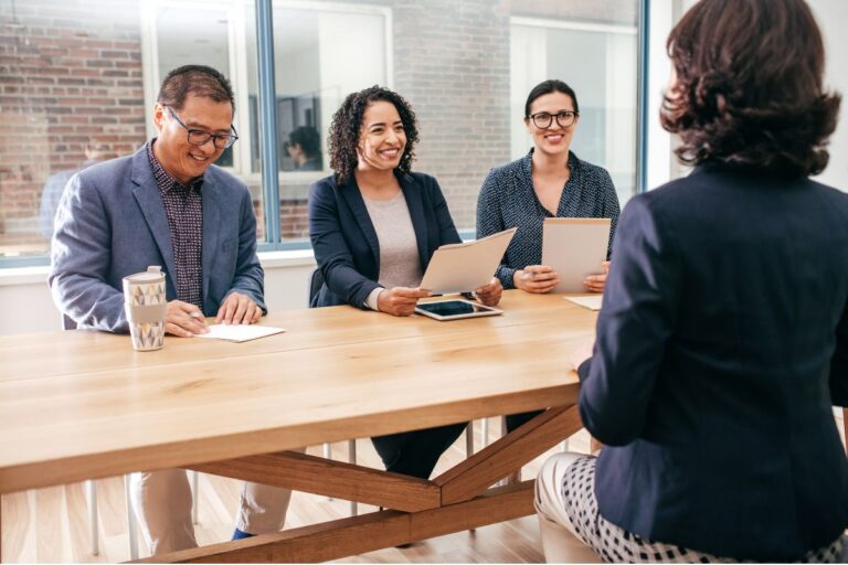 A group of professionally dressed individuals in a panel interview setting, illustrating a high-volume hiring process.