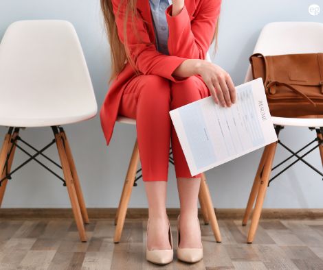 Lower shot of a woman sitting in a chair holding her resume