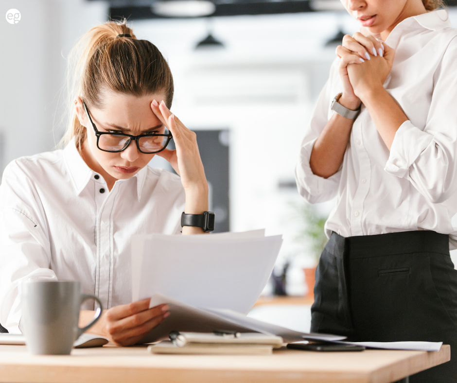 Two women looking nervously at paperwork