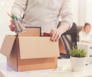 Person packing up a cardboard box with work items in resignation