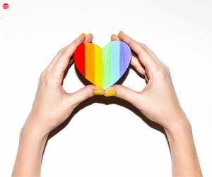 Hands holding a pride rainbow heart