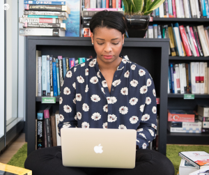 African American woman using a laptop surrounded by books
